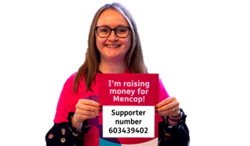 A woman holding up a sign which says I'm raising money for Mencap! followed by her Mencap supporter number