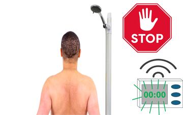 A man standing in a shower.  Beside the shower is a timer flashing and making a noise and a stop sign.