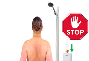 The back of a man standing in a shower with no water coming out of it. On the shower unit is an empty timer with an arrow pointing downwards and a stop sign beside the shower.