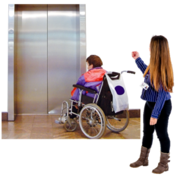 A person in a wheelchair waiting for a lift with someone showing them the way.
