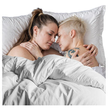 Two women lying in bed together with their arms around each other.