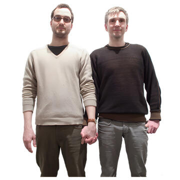 Two men standing beside each other holding hands.