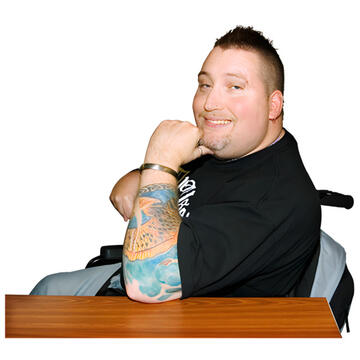 A man sitting and smiling with his elbow on a table.