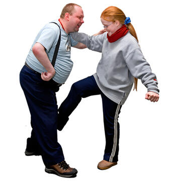 A woman grabbing a man by the shoulder and kicking him.