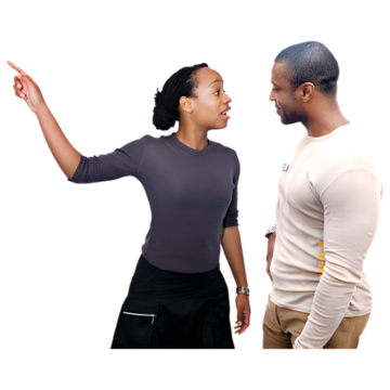 A woman with her arm raised pointing behind her and talking to a man.