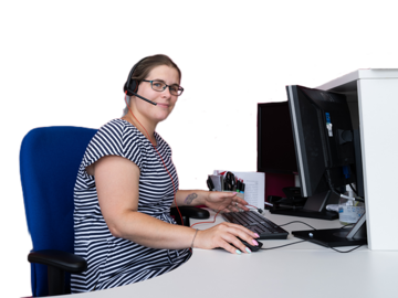 A woman at a computer desk wearing a phone headset