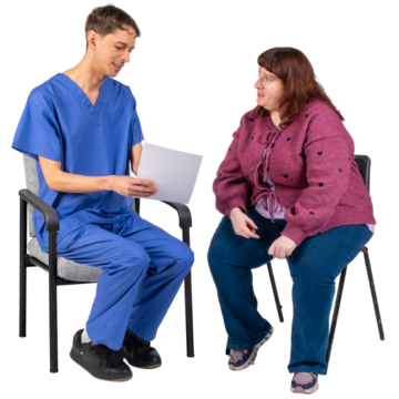 A nurse talking and showing a piece of paper to a woman.