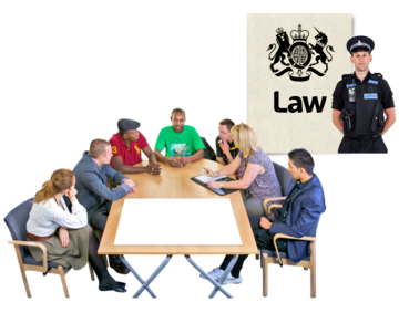 A group of people sitting around a table at a meeting with a picture behind them of the law and a policeman.