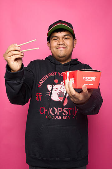 Arjhay holding a Chopstix meal box and chopsticks