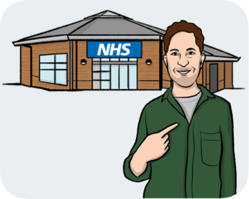A man standing in front of an NHS building pointing to himself.