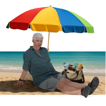 A man on a beaching keeping cool in the shade under an umbrella