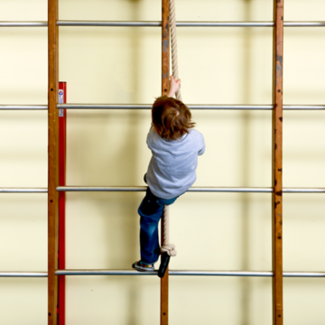 A child climbing on bars in a school gym