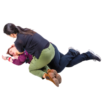 A person fainted on the floor with a carer knelt down next to them checking if they're ok