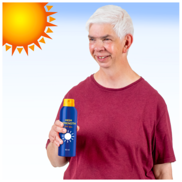 A man on a very sunny day holding a bottle of sun cream