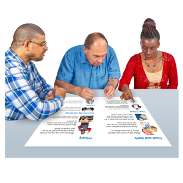 Three people examining a printed sheet at a table.
