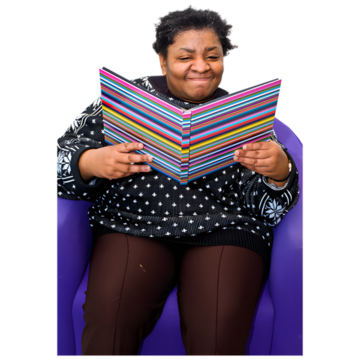 A woman sitting in a chair reading information in a folder and smiling.