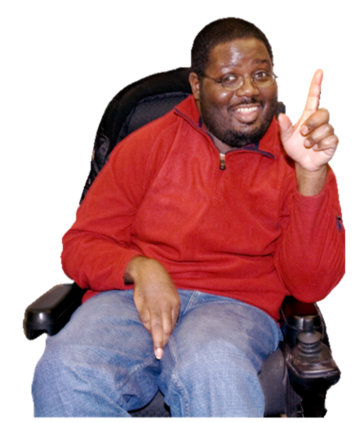 A man in a wheelchair smiling with his index finger raised.