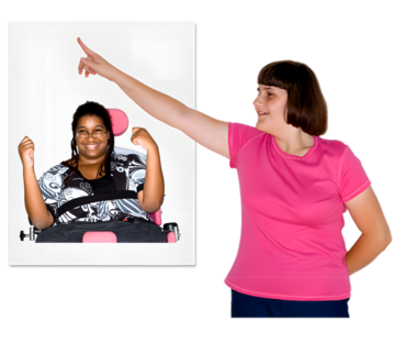 A woman pointing to a board which has a picture of a smiling woman in a wheelchair on it.