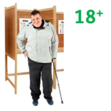 A man standing by a voting booth with 18+ beside him.
