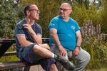 Two men on a bench talking in a garden