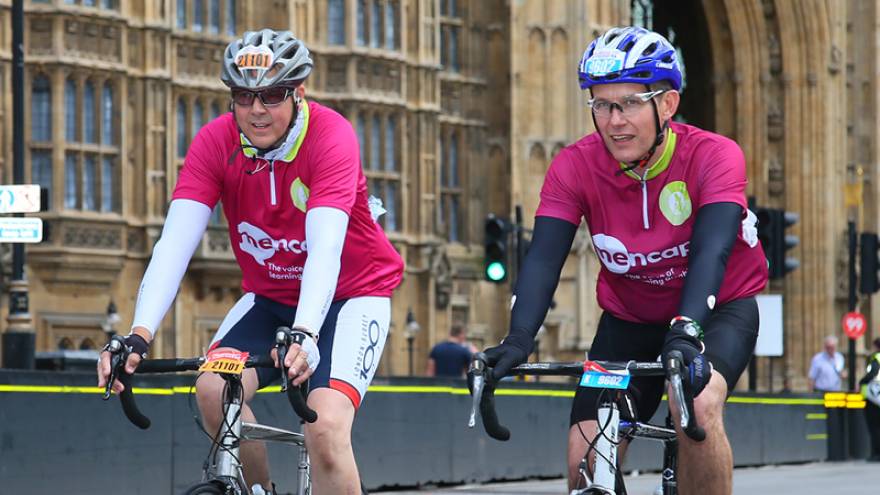 Two men on bikes, cycling past the Houses of Parliament in London