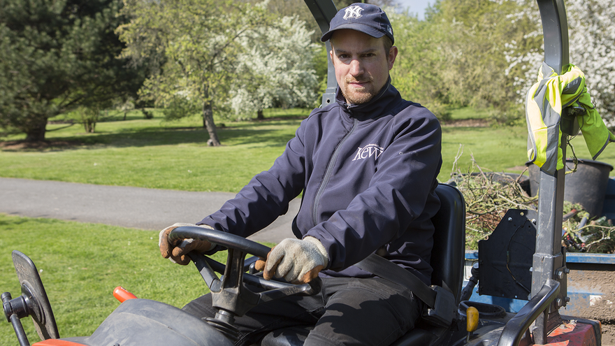Young man sat on a ride-on lawnmower outside