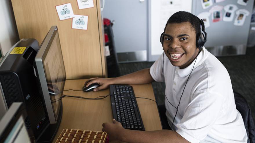 Young man sat at computer smiling