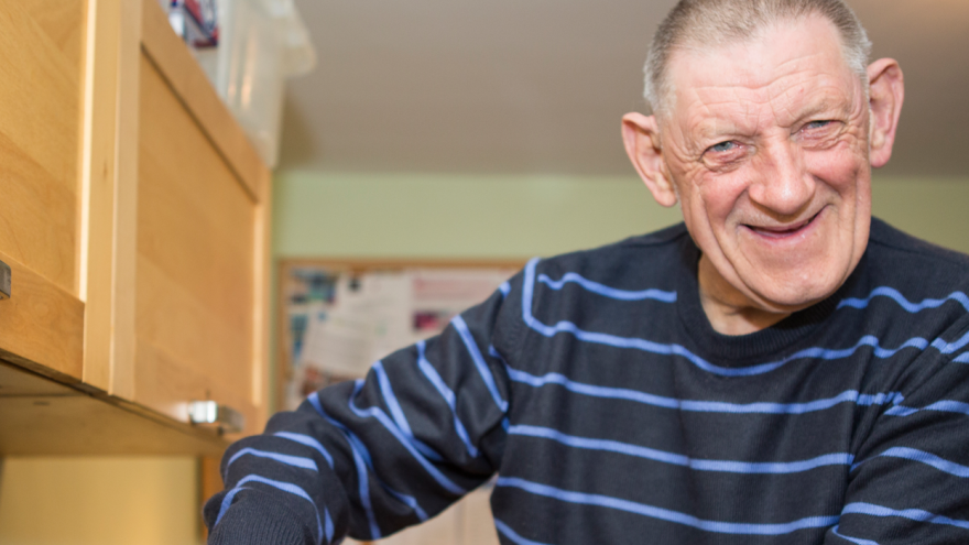 Older man stood smiling in a kitchen