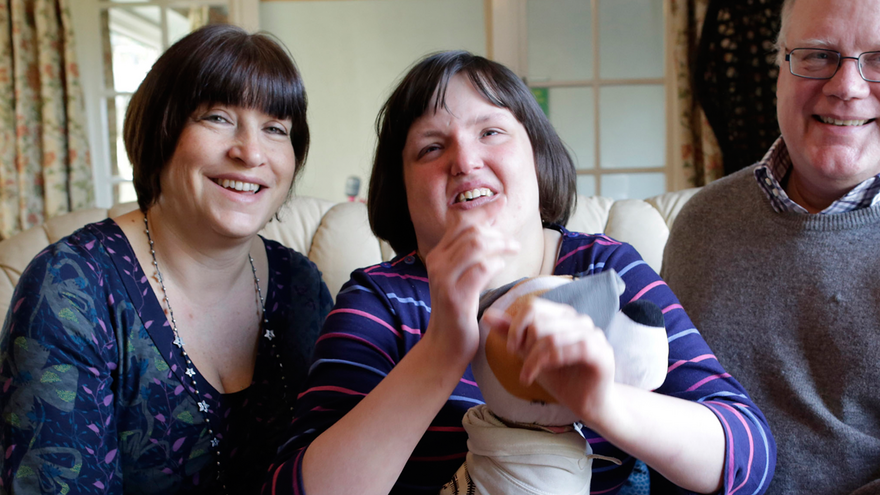 Mother and father sat either side of their daughter in living room
