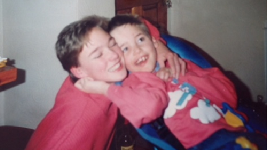 Woman smiling with her eyes closed with her arm around a child in a seat next to her