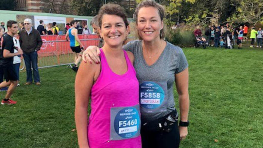 Two women wearing running clothing stood next to each other outside 