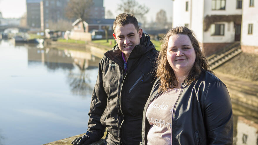 Man and woman stood by lake.