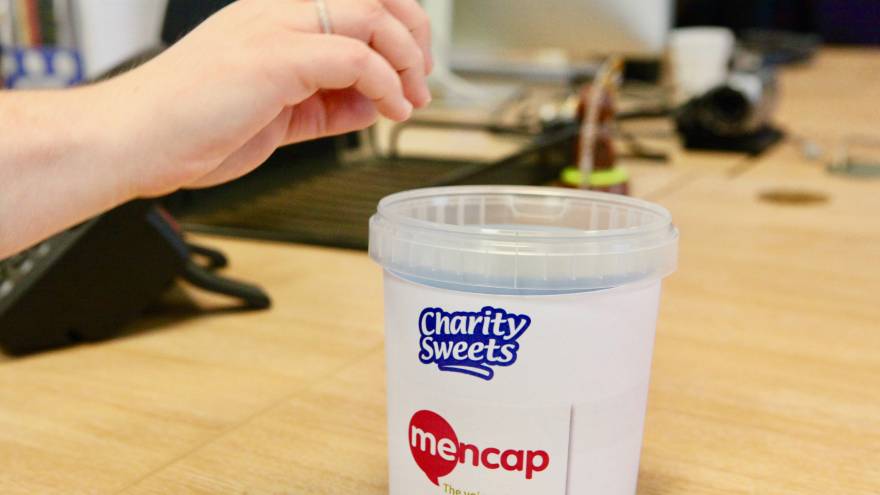 Hand reaching for a pot of Mencap sweets.
