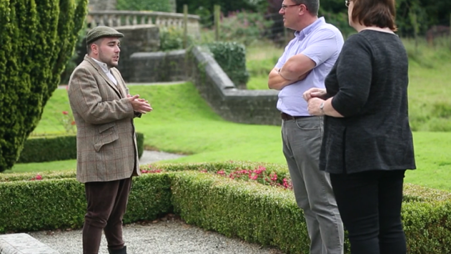 Man stood speaking with two other people in grounds of National Trust property.