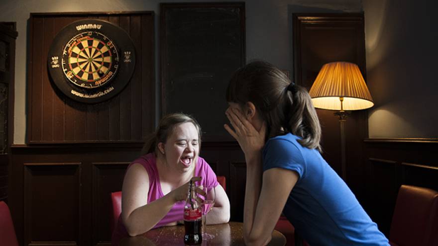 Two women sat together at table in a pub.