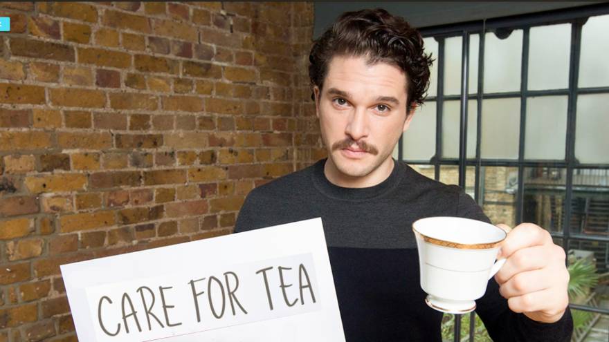 Kit Harington holding a tea cup and sign