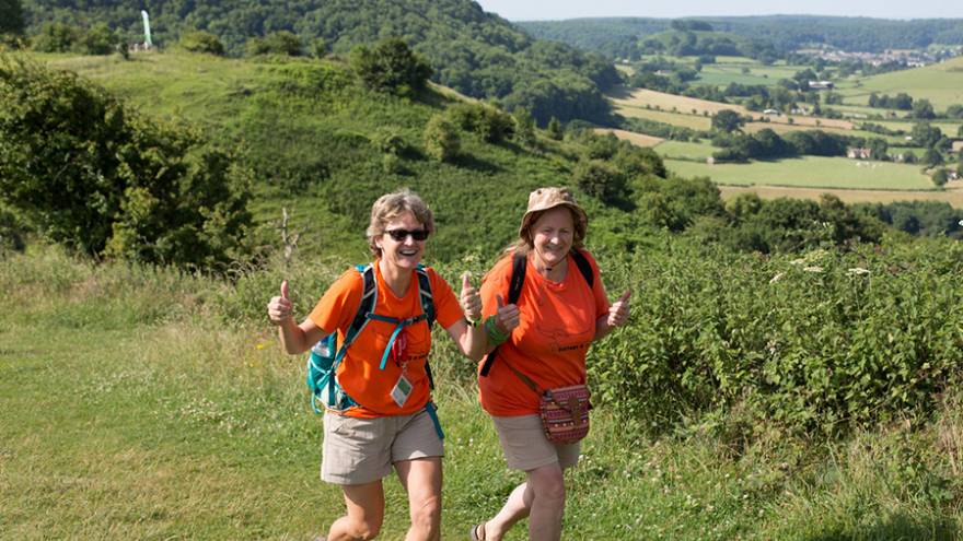 Two women walking through sunny coutryside.