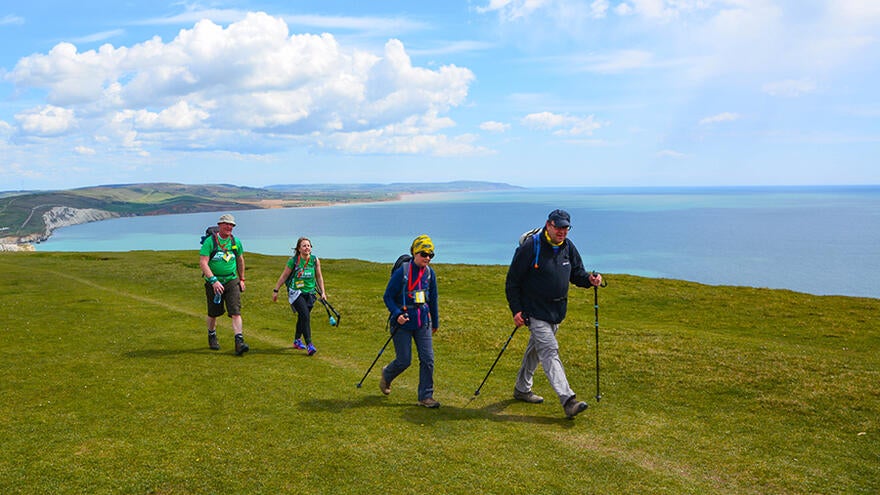 Four walkers walking along country path on clifftop.