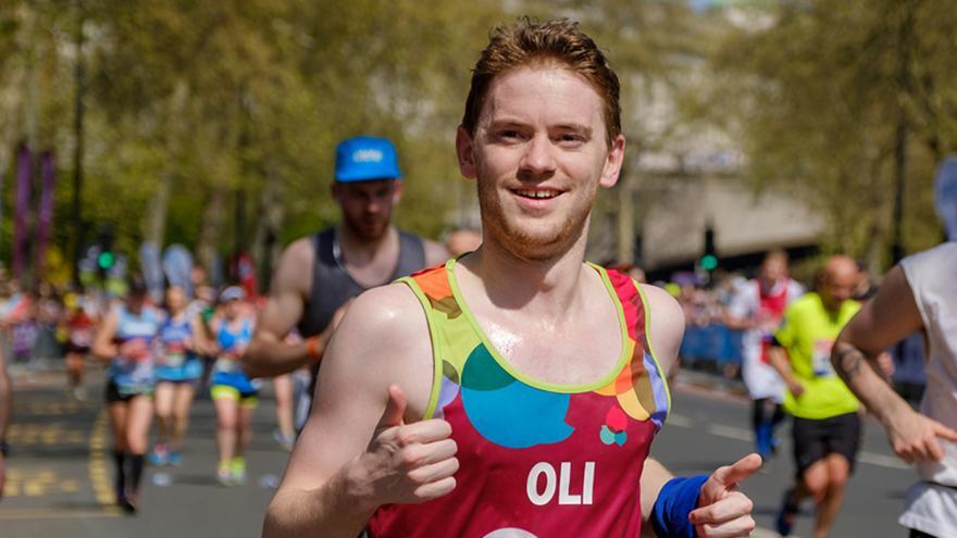 Male runner wearing Mencap running vest looking into camera whilst taking part in running race.