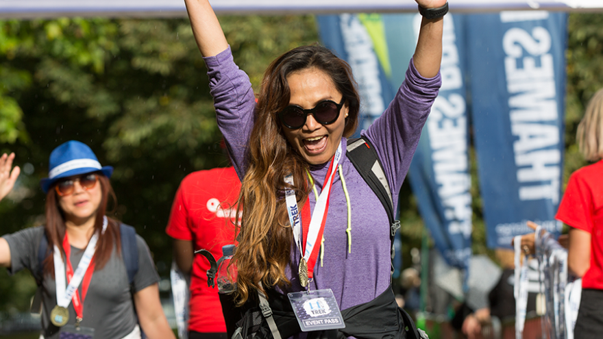 Woman celebrating holding her arms above her head after crossing finish line.