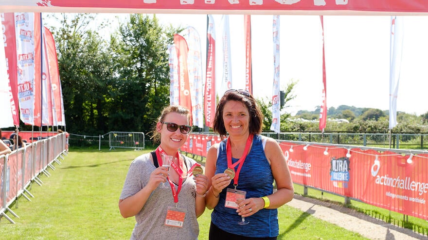 Two people stood at finish line of walking event holding medals.