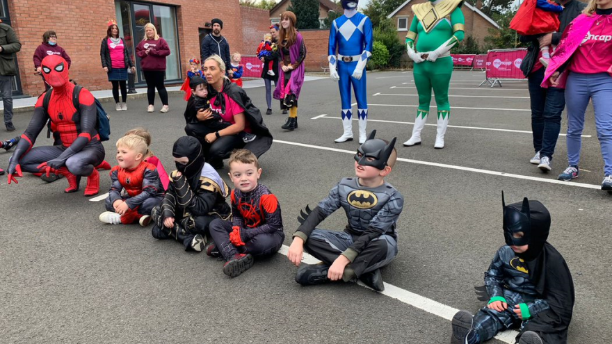 Adults and children dressed as superheros outside the Mencap Centre building