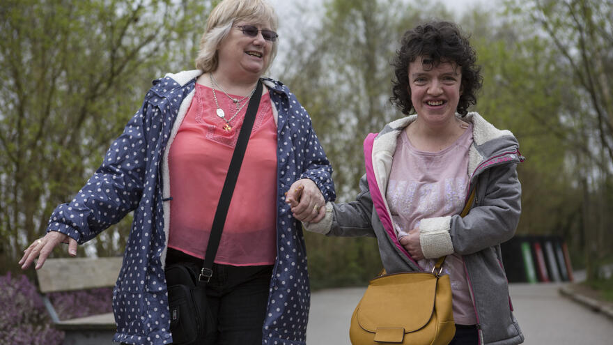 Woman and young woman walking in a park hand in hand