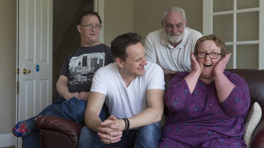 A group of four people on a sofa laughing and smiling