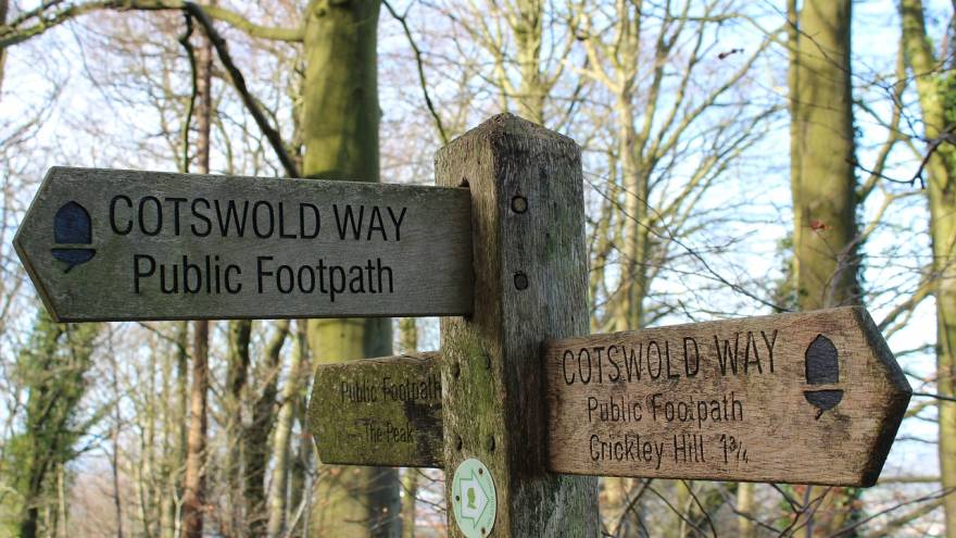a wooden sign post pointing to the Cotswold Way
