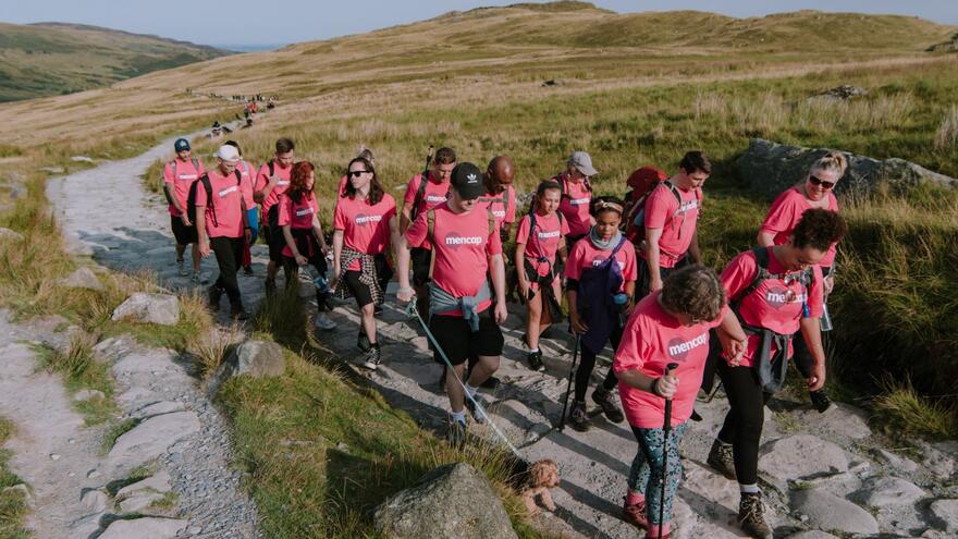 A group of hikers all in Mencap Tshirts walking up a moorland path