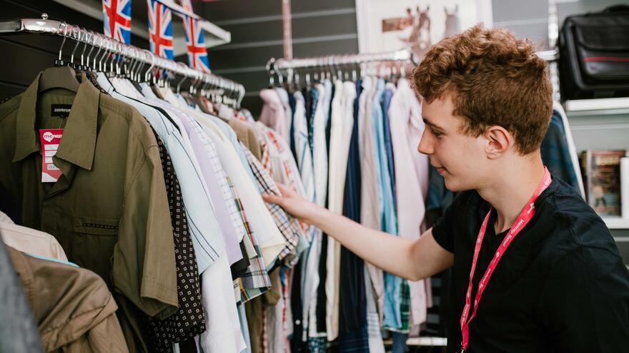 A man looking through a rail of men's shirts