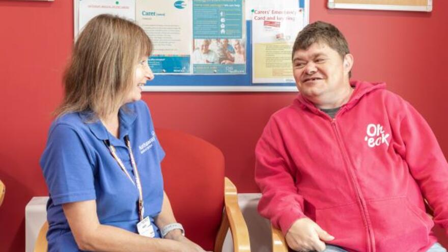 A nurse talking to a man in a surgery waiting room