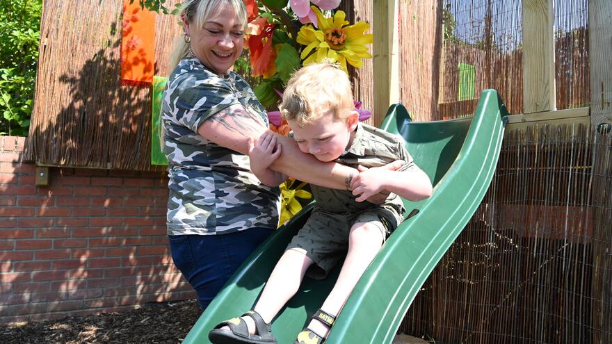 A mother helping a child go down a slide
