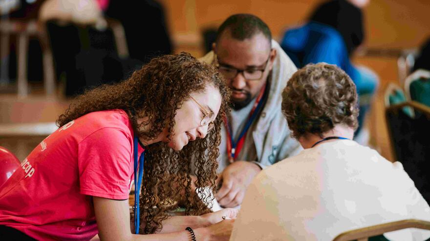 A woman is helping two people fill out a form